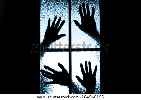 Scared boy behind glass door showing one hand