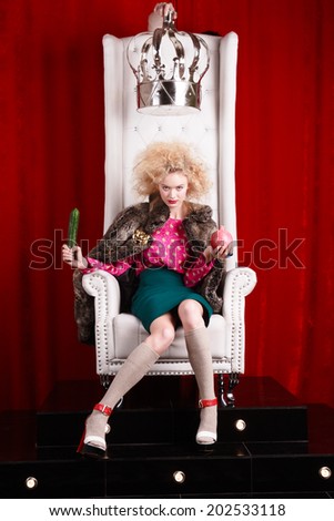 princess woman in fur coat sitting on throne. studio shot