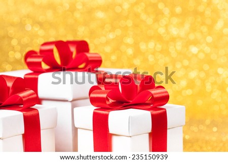 gift box with red ribbon, glittery gold background