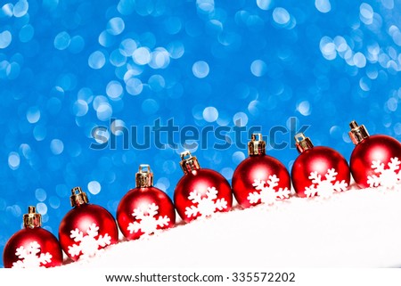 christmas red balls in snow on blue glitter background. studio shot