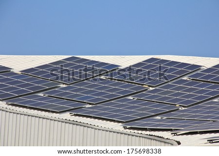 Solar panel on  roof reflecting the sun and the cloudless blue sky