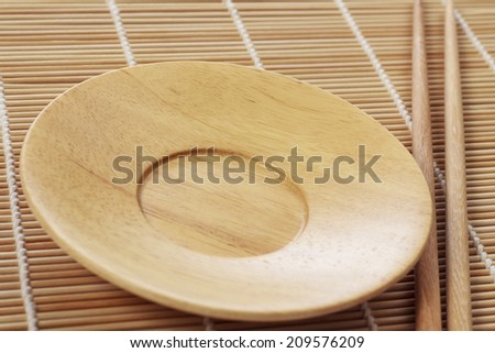 Empty plate and chopsticks on bamboo table
