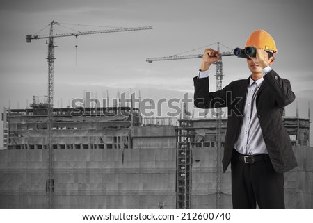 professional builder wearing helmet and hand show up . man see vision forward and success of future on the background of a new high-rise apartment buildings and construction cranes