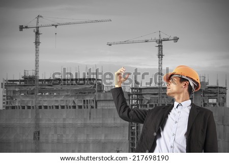 professional builder wearing helmet and hand show up . Man see vision forward and success of future on the background of a new high-rise apartment buildings and construction cranes.