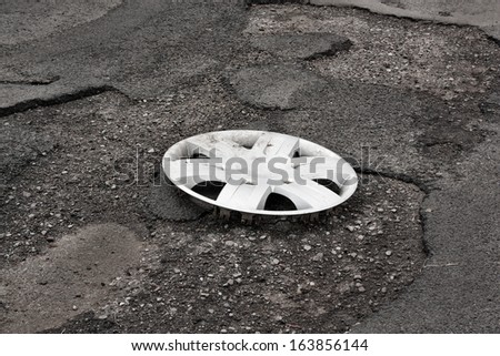 Wheel cover clipped on the damaged road with holes