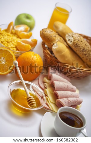 Breakfast with coffee, bread, honey,  juice, fruits, egg, ham and cheese