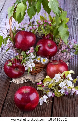 apples in a basket with apple flower on wooden table