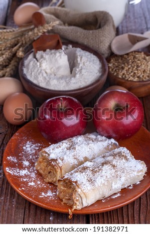 apple pie on a wooden table with flour and grain in the background