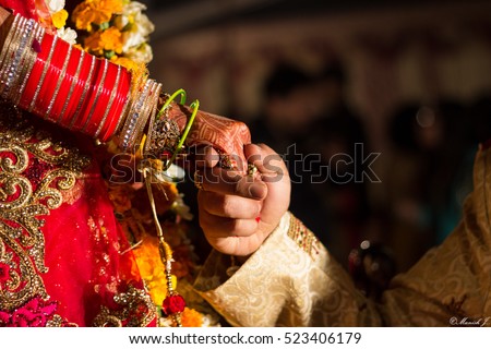 Close up of hands of bride and groom.\
A close up of hands of a groom holding his bride\'s hands at an Indian wedding.