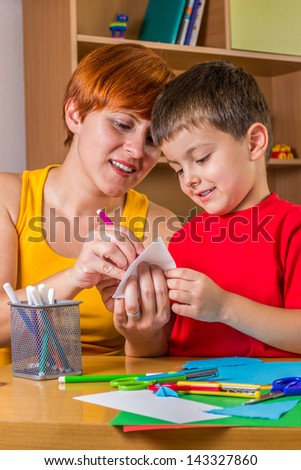 Mother helping her son to make paper craft