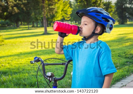 Little boy drinking water by the bike