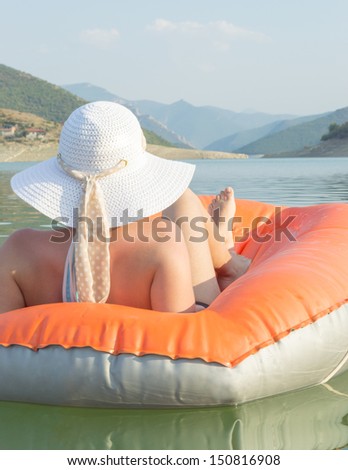Beautiful young woman relaxing on air mattress at the lake