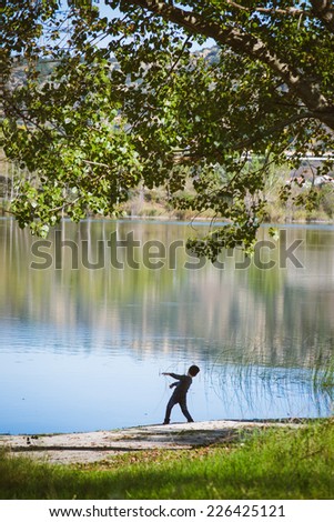 Boy throwing rocks by the lake