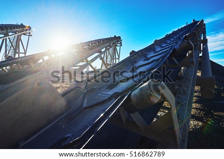 Industrial background with gravel crusher. Conveyor belts for the mining of gravel on the background of the rising sun