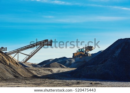 Industrial landscape. Extraction of gravel. Bulldozer Working in the background of sky and gravel hills.