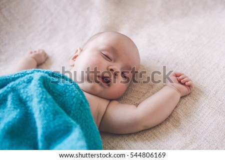little boy sleeps under a blanket on the bed