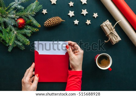 Christmas table with various items. Woman\'s hands putting a letter in an envelope