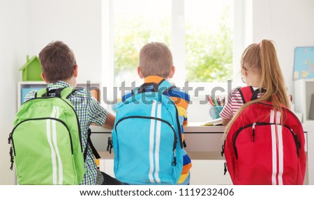 Children sitting in the room with books and backpacks. Pupils reading at school