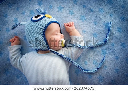 4 month old baby in owl hat sleeping on blue blanket