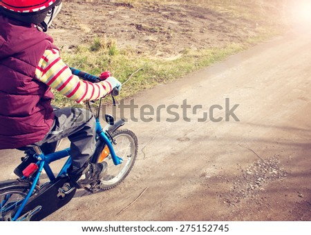 Boy on bike at gravel road in spring