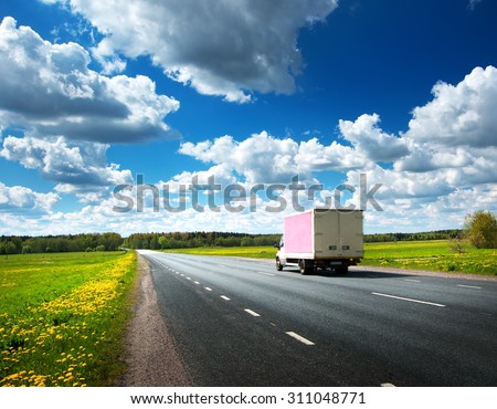 asphalt road on dandelion field with a small truck