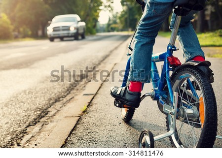 A boy on bike and a car on the road