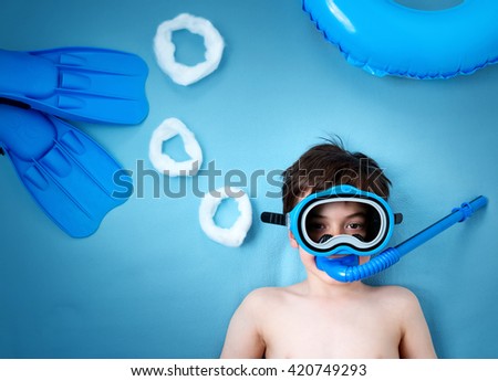 Child lying on blue blanket with swimming mask and flippers