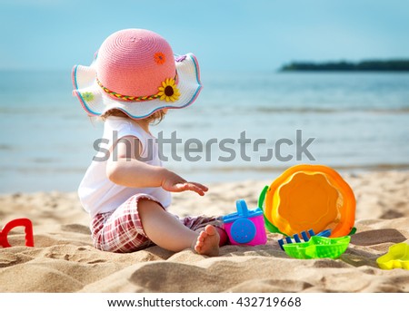 one year old girl shouting at the sea with bucket