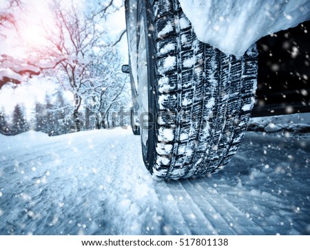 Car tires on winter road covered with snow. Vehicle on snowy alley in the morning at snowfall