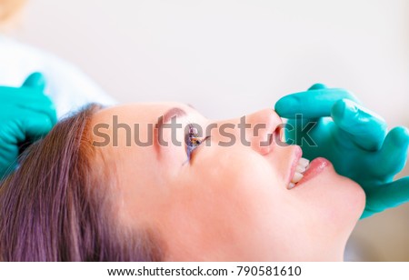 Cosmetic surgeon examining female client in office. Doctor checking woman\'s face, nose before plastic surgery. Surgeon or beautician hands touching woman face. Rhinoplasty