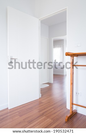 White door in modern home\'s room with wood floor and down stair, clothes hanger.