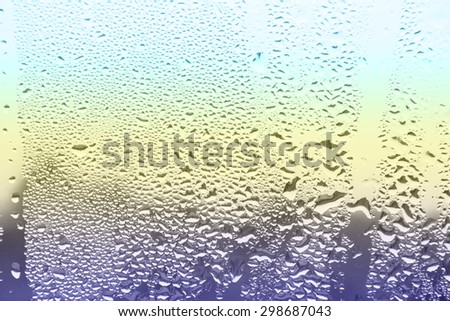 Drops of rain on window in colour background
