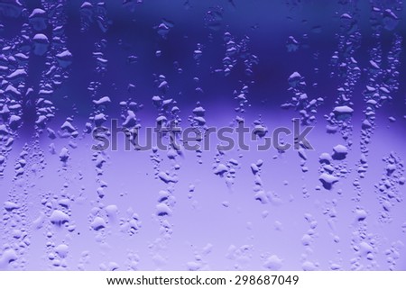 Drops of rain on window in purple shade
