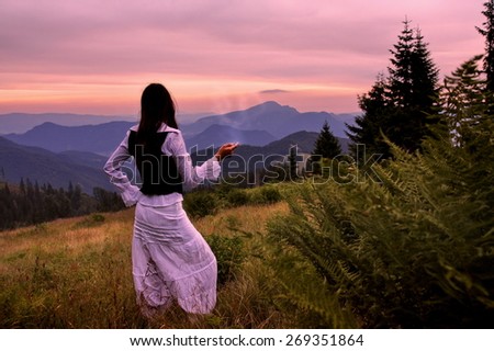 Mystic woman in ancient dress alone in a beautiful romantic sunset landscape