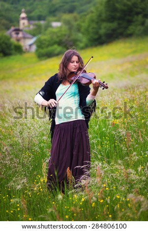 violinist on a meadow full of flowers, Young girl playing music instrument