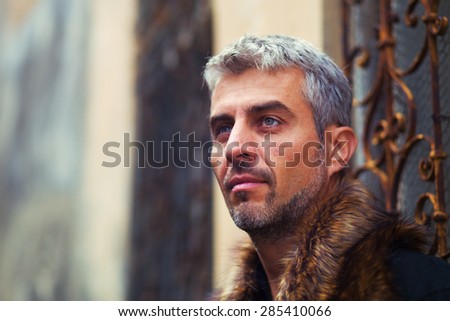 Portrait of a sexy man in wolf  fur and ornamental medieval window on background.