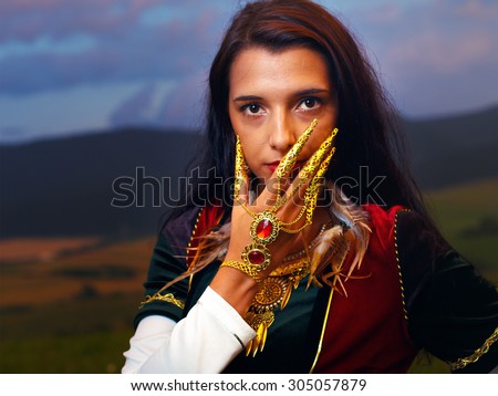 Smiling  Young woman with ornamental dress and hand jewel. Natural background
