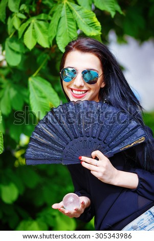 Smiling young woman smelling Spring Magic, Magical Glass sphere in hand and beautiful ornamental fan.
