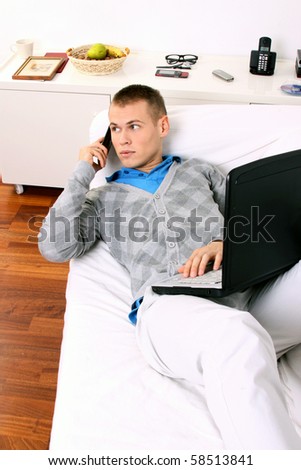Handsome young relaxing man using laptop and lying on the sofa