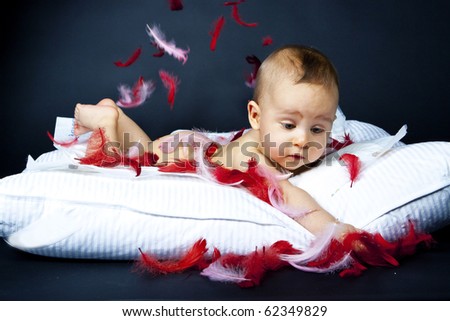 baby lying on the pillow in in white with red fluff