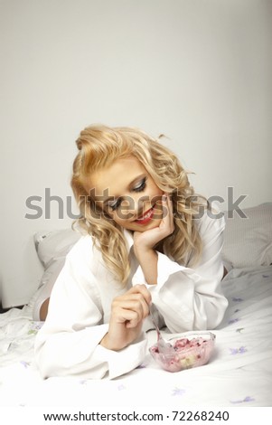 Beautiful woman eating in bed