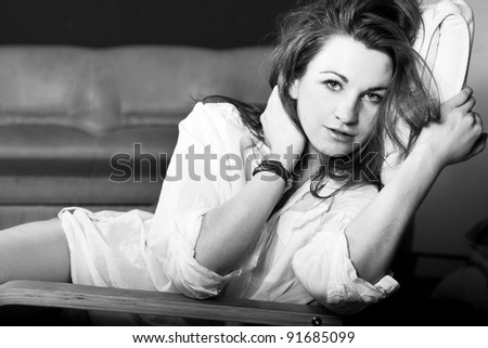 Black and white portrait of a beautiful  young woman in t-shirt smiling siting on her sofa at home.