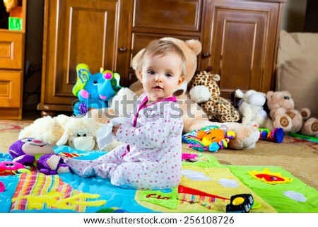 little baby on the play mat with toys smiling