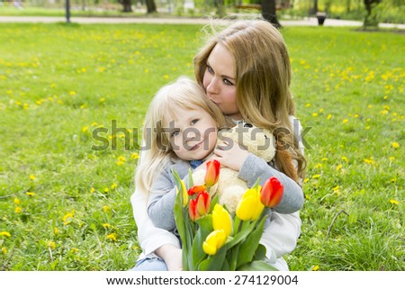 Mother and daughter with flowers playing in spring park. Mothers day celebration concept
