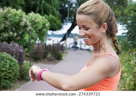 fitness smiling woman looking at heart rate monitor on hand
