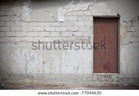 Nice textured wall, big white bricks , plaster fallen off, rusty metal door.