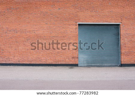 Big metal garage door on big brick wall.