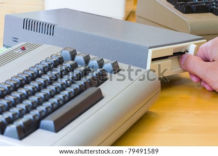 Male hand putting in a disc in a disc drive to an old vintage computer