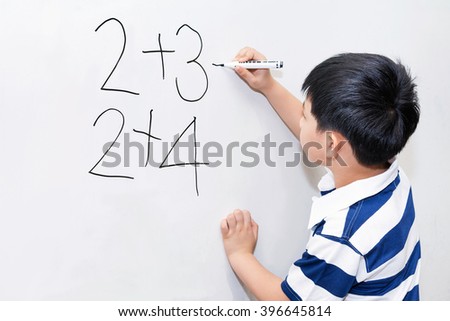 Asian boy learning calculation on white board in classroom.