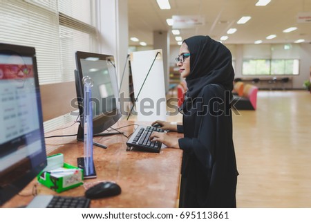 Arabic woman typing on computer , searching data in the library.
